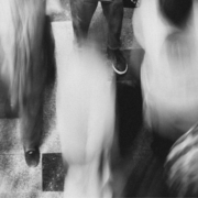 A person stands motionless as people zip by in a blur.