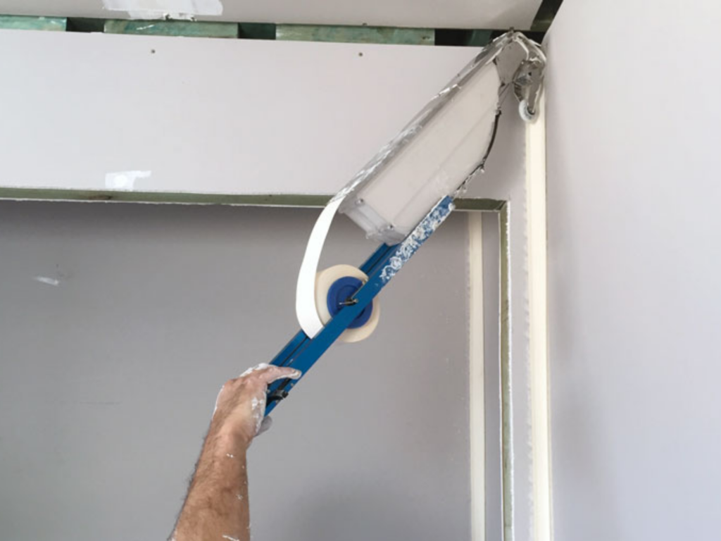 Drywall finisher is able to reach ceiling joints comfortably from the ground thanks to the extended reach handle of the Tapepro Mud Box Pro.